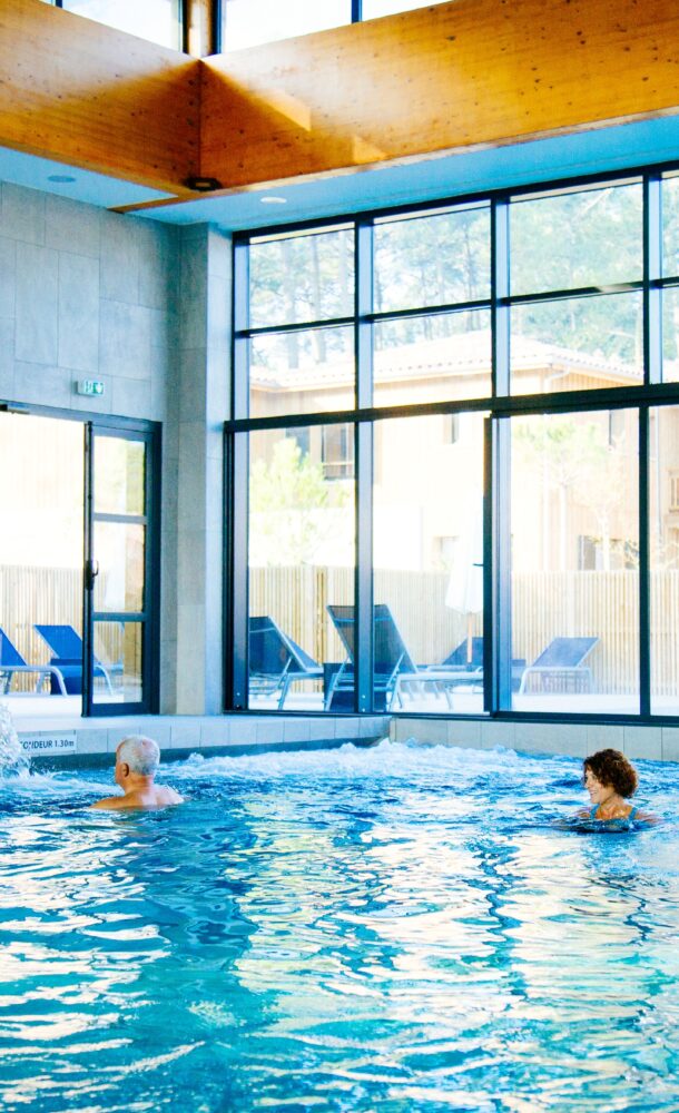 Une femme se détend dans la piscine intérieur au Balneo Serge Blanco à Claouey.