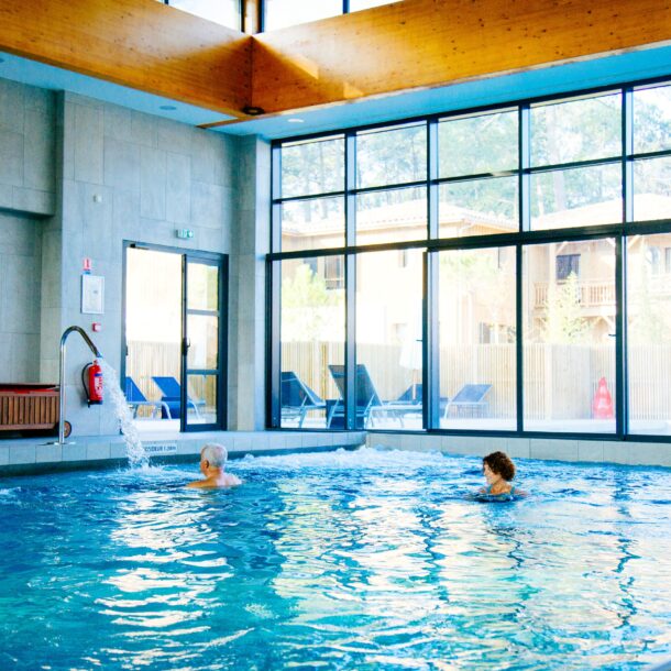 Une femme se détend dans la piscine intérieur au Balneo Serge Blanco à Claouey.