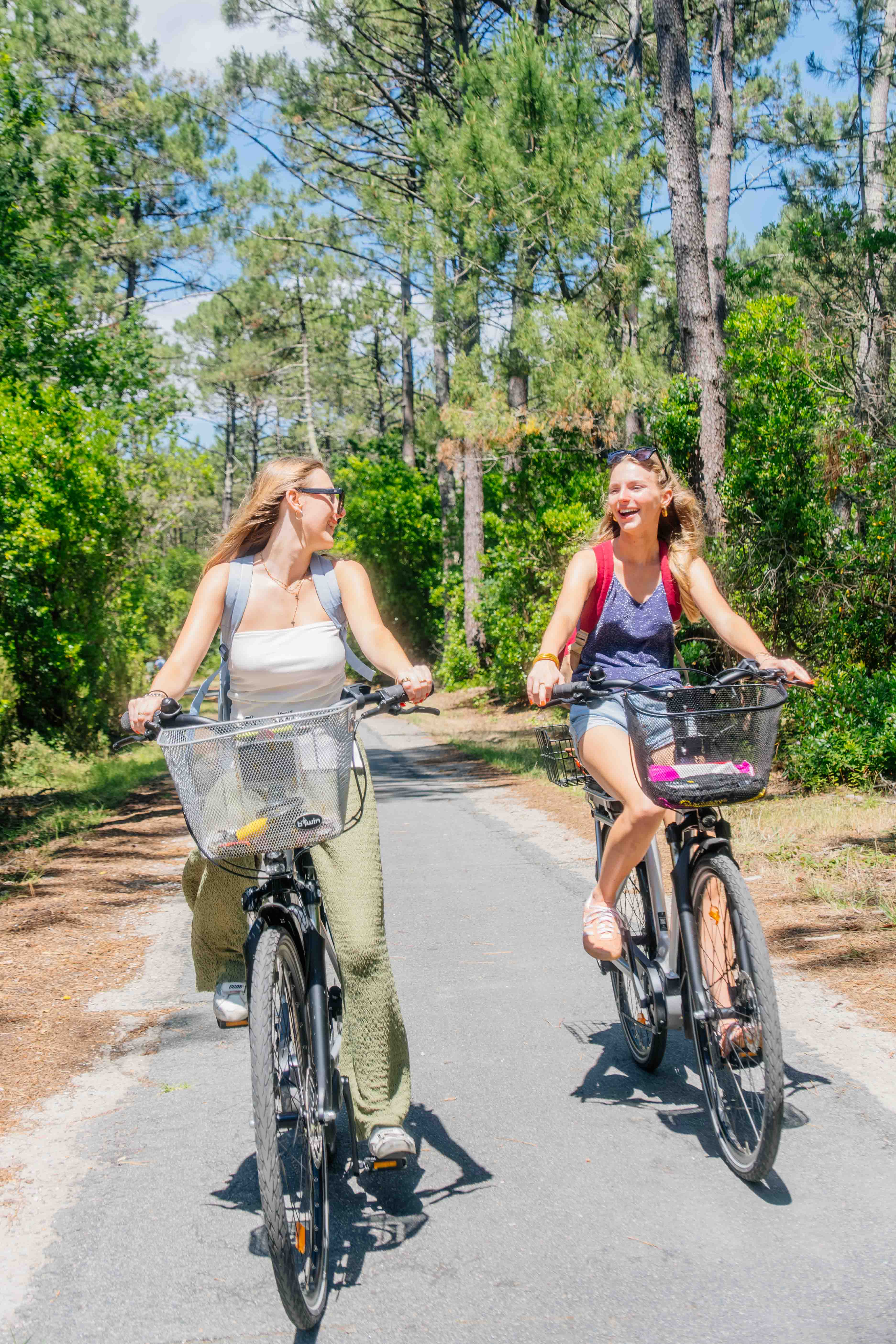 Deux filles sont sur leurs vélos en train de se balader et de rigoler.