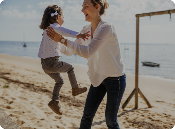 Une mère porte son enfant sur la plage.
