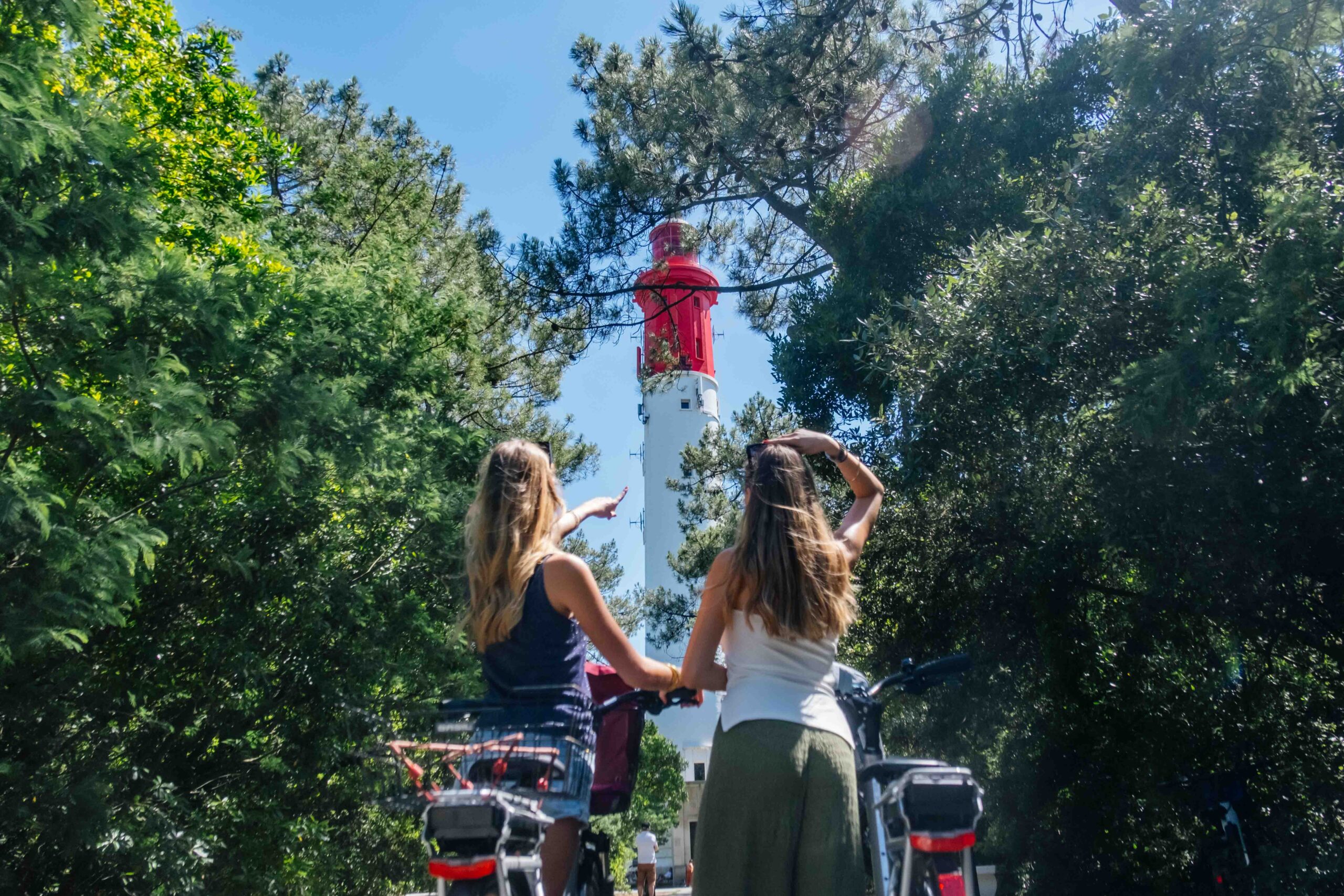 Deux filles, vélos à la main, regardent le phare.