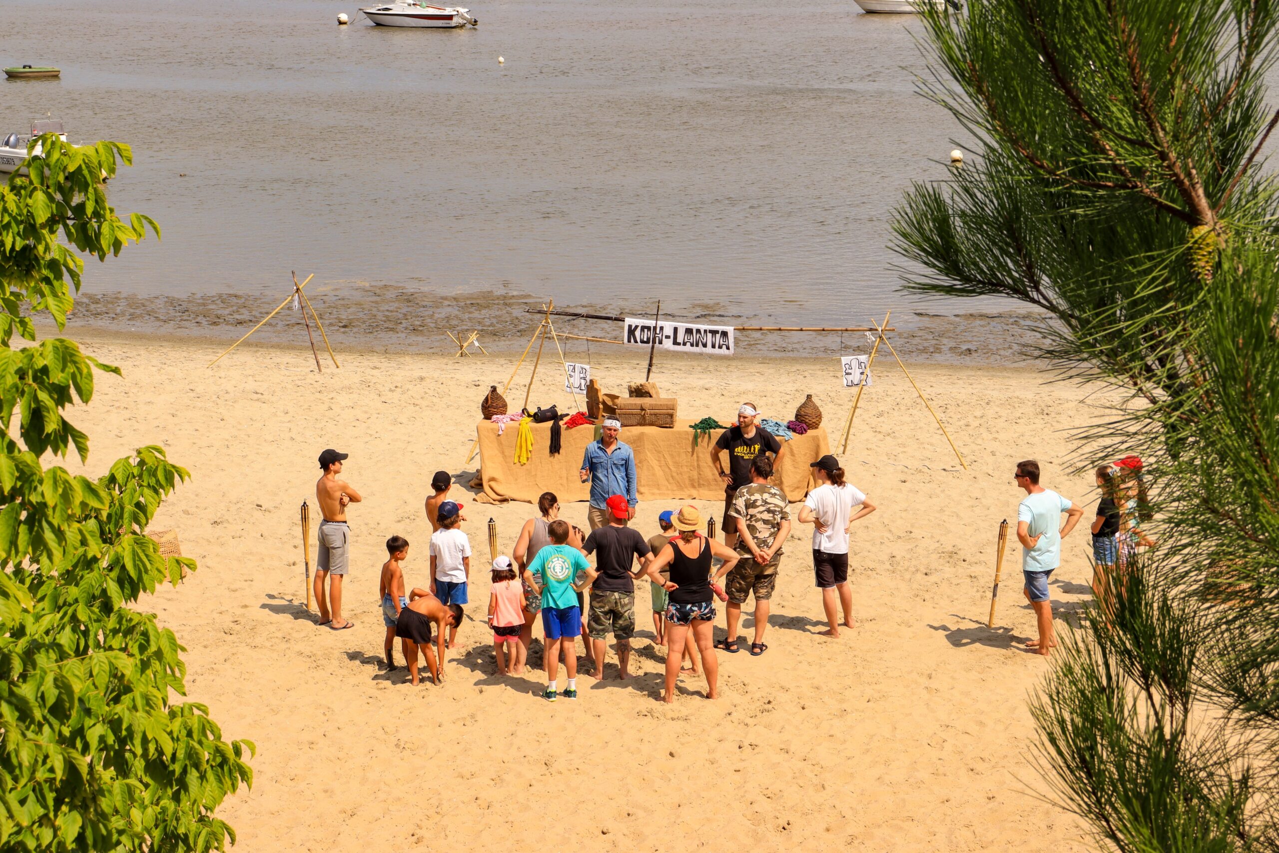 Un groupe de jeunes s'amuse sur la plage du Bassin à Claouey, participant à un Koh-Lanta, une activité organisée par le camping Les Pastourelles.