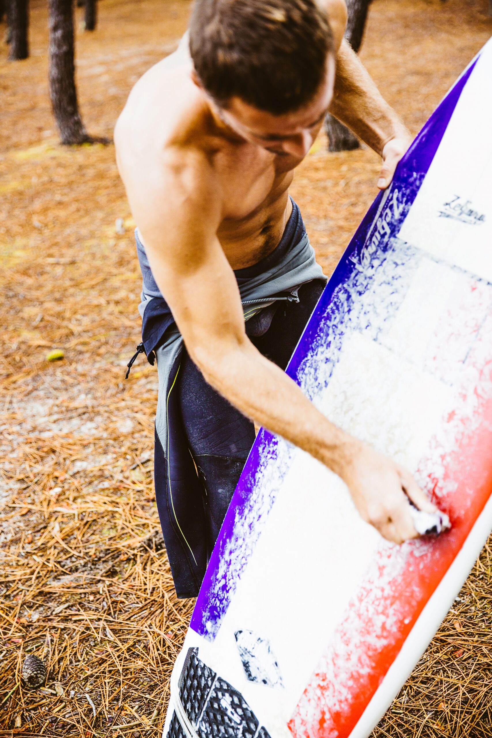 Un surfeur met de la wax sur sa planche.