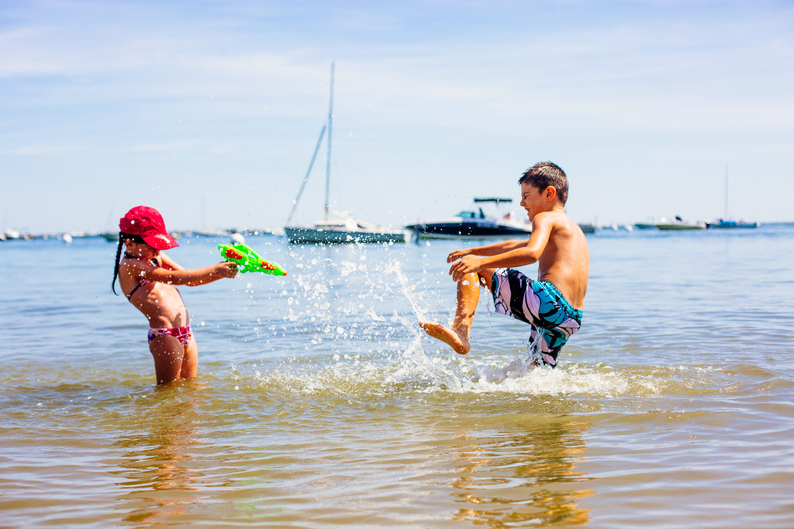 Des enfants s'amusent dans le bassin avec un pistolet à eau.