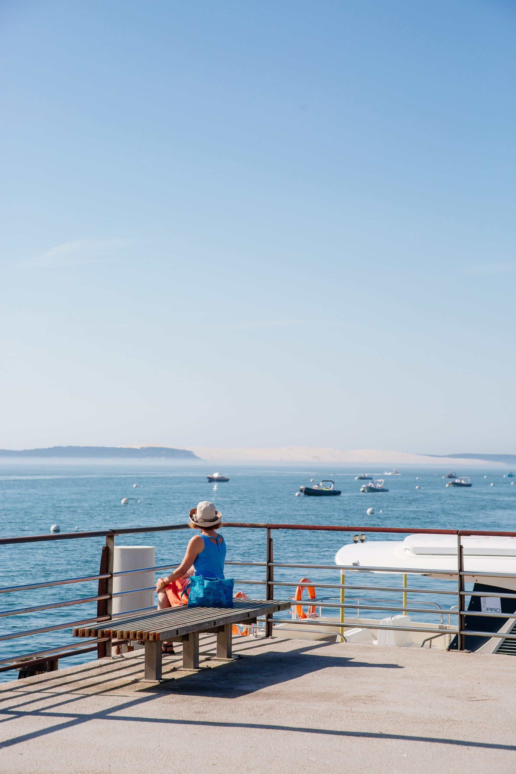 Une femme est assise sur le port, contemplant le Bassin.