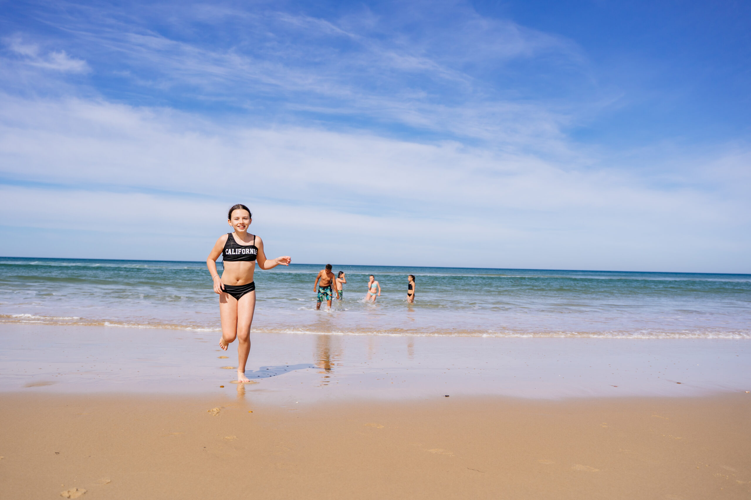 Un enfant sort de l'océan en courant.