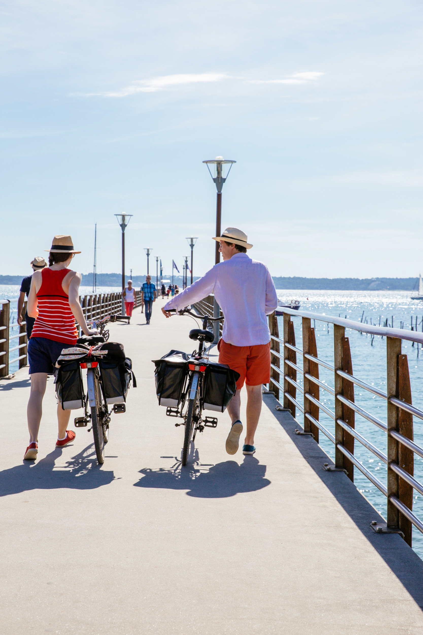 Un couple marche, vélos à la main, sur le pont en direction de la navette pour Arcachon.