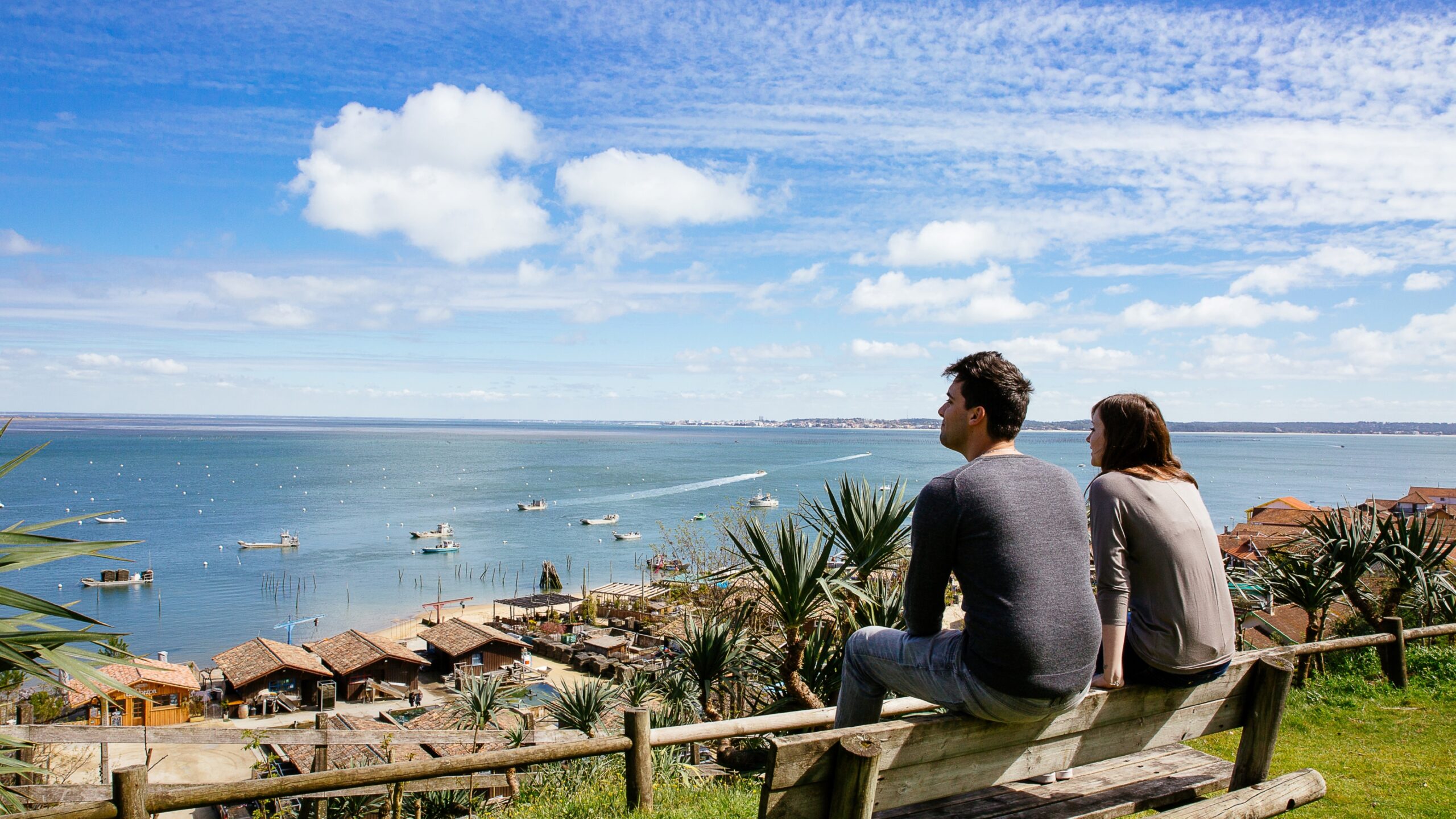 Un couple est posé sur un banc en train de regarder le bassin.