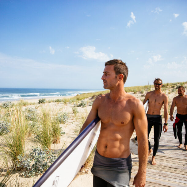 3 hommes marchent vers le Truc Vert pour leur session surf.