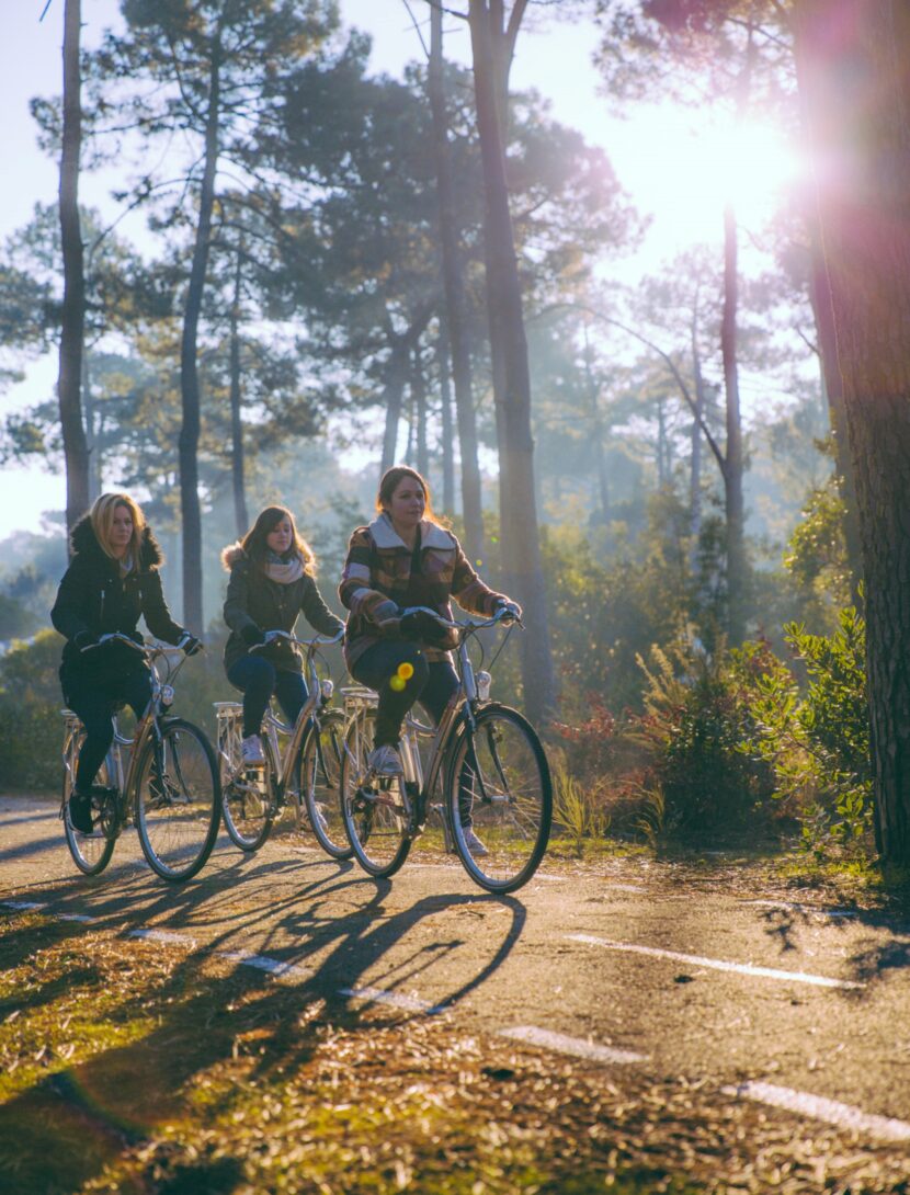 3 filles sont en train de se balader à vélos en automnes dans une forêt.