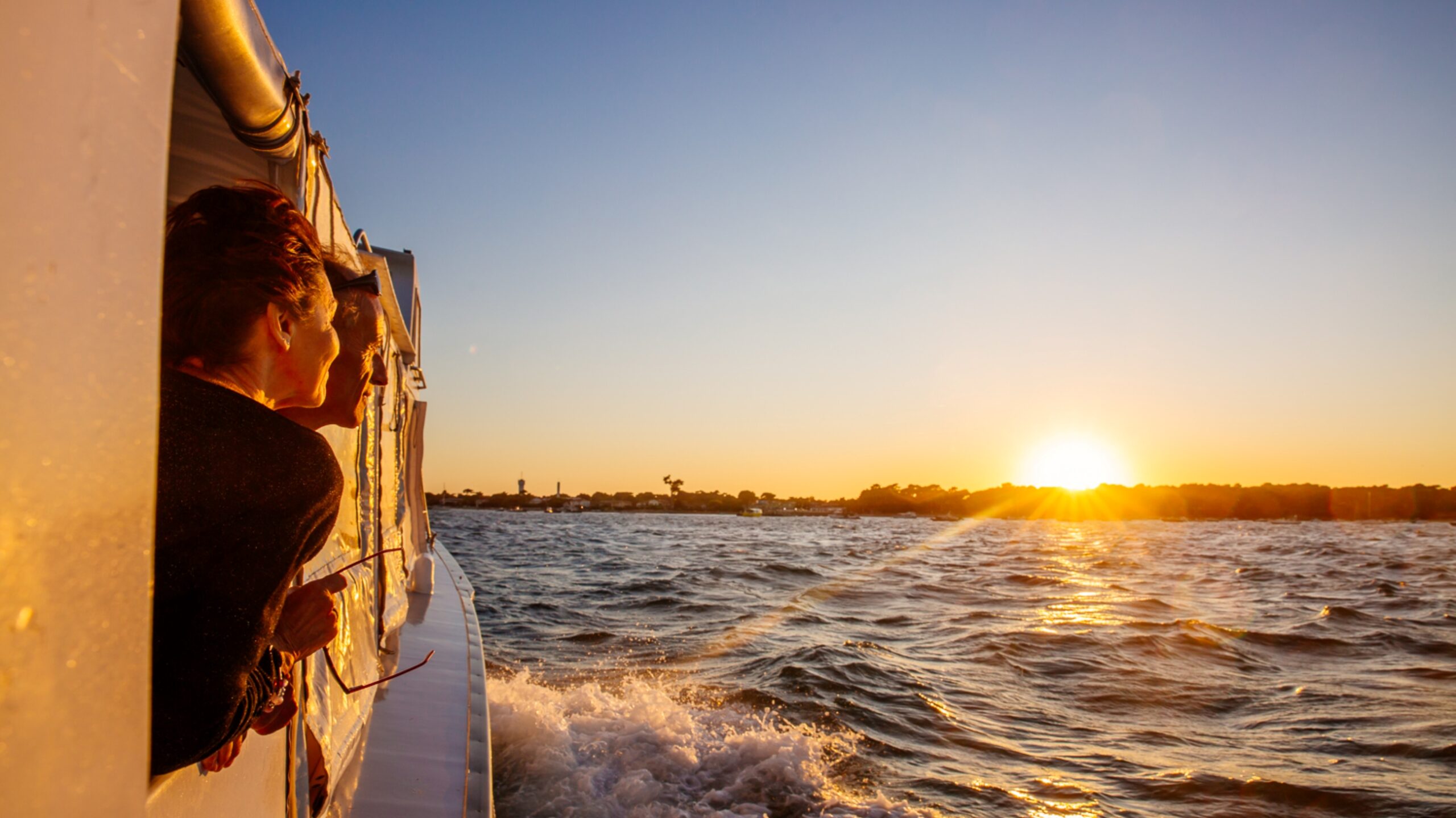 Une femme regarde le coucher de soleil sur son bateau pendant la traversée du bassin.