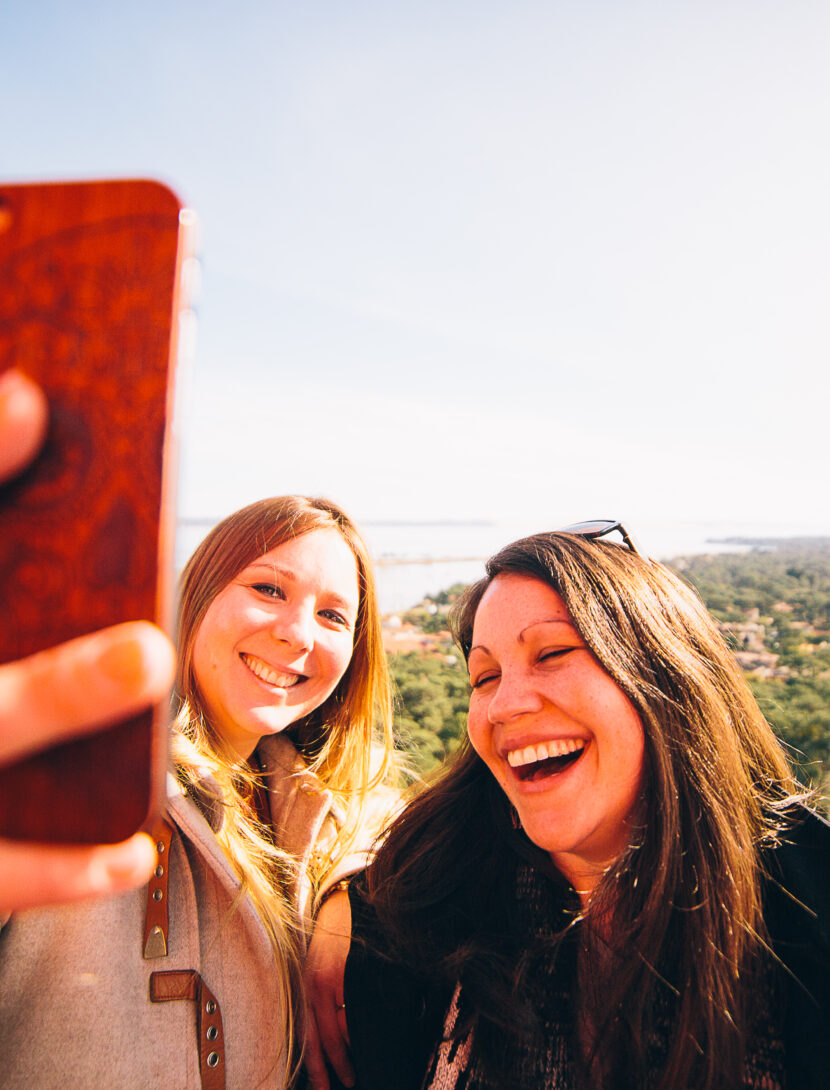 Deux amies, remplies de joie, immortalisent leur moment au sommet du phare en prenant une photo souvenir, avec une vue imprenable qui ajoute à la magie de l'instant.