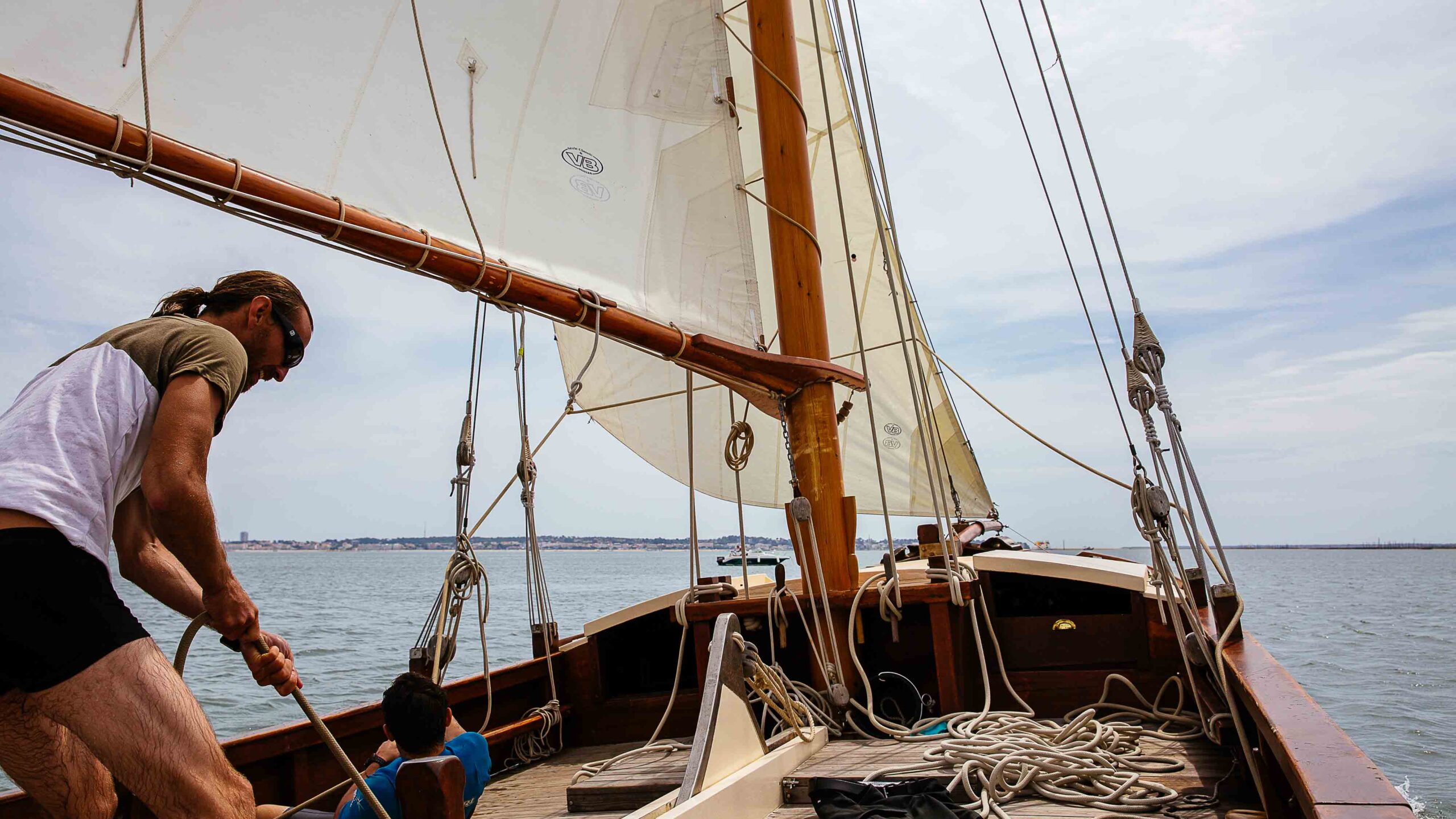 Un homme tire sa voile sur son voilier pour prendre de la vitesse.
