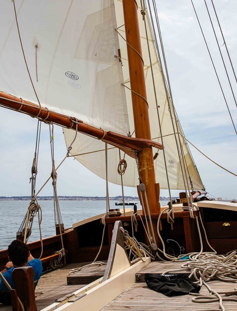 Un homme tire sa voile sur son voilier pour prendre de la vitesse.