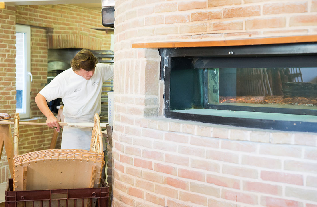 Un boulanger sort du pain artisanal tout juste cuit du four dans une boulangerie traditionnelle à Lège-Cap Ferret, sur le Bassin d’Arcachon.