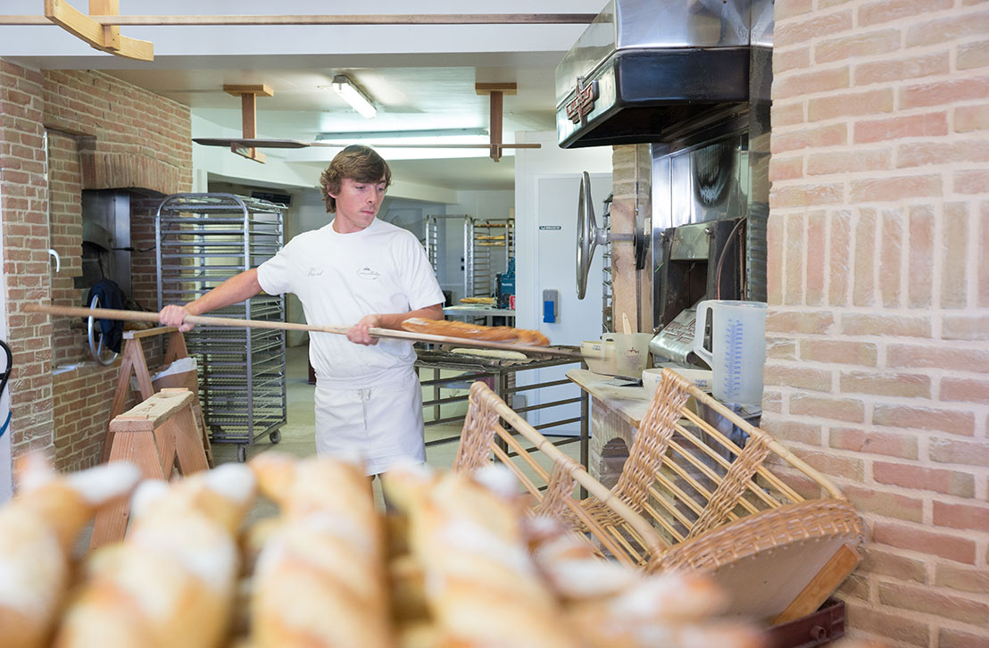 Un boulanger sort du pain artisanal tout juste cuit du four dans une boulangerie traditionnelle à Lège-Cap Ferret, sur le Bassin d’Arcachon.