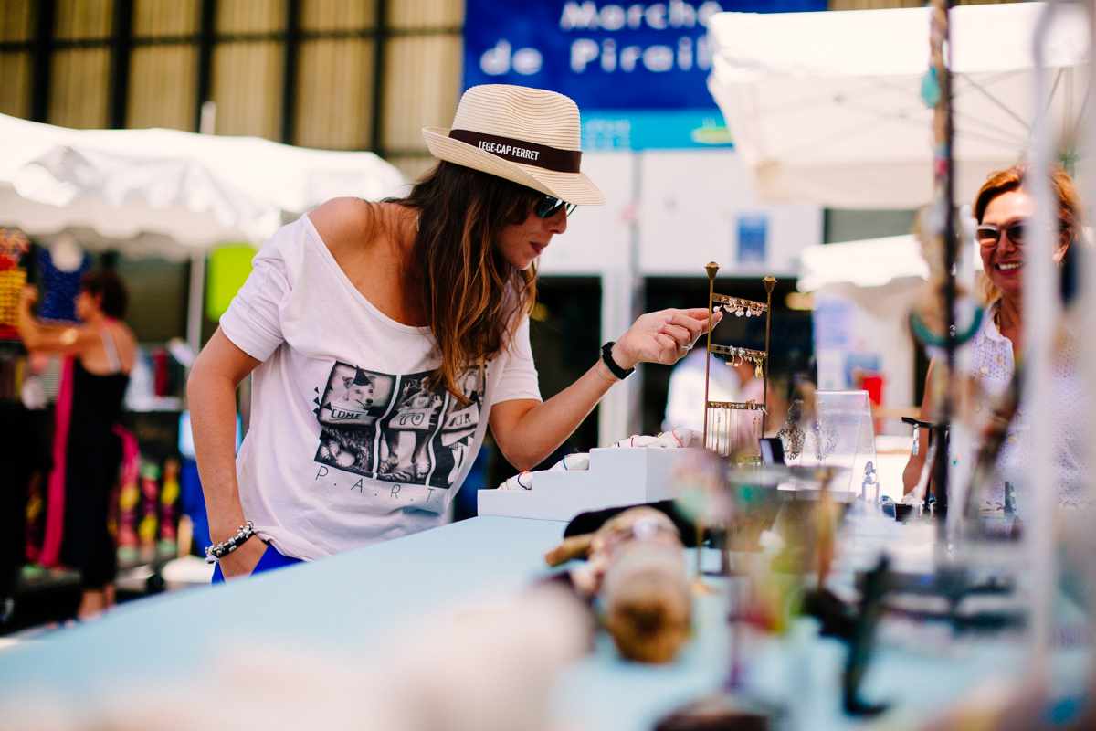 Une femme regarde des boucles d'oreilles artisanales sur un stand de bijoux au marché extérieur de Piraillan à Lège-Cap Ferret, sur le Bassin d'Arcachon.